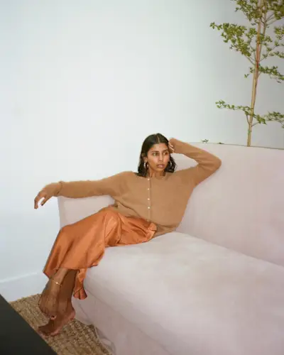 Monikh wears a tan cardigan and a gold maxi slip skirt.
