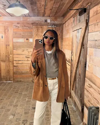 Influencer @lornasymphony wears a grey cardigan with a brown suede blazer and white jeans.