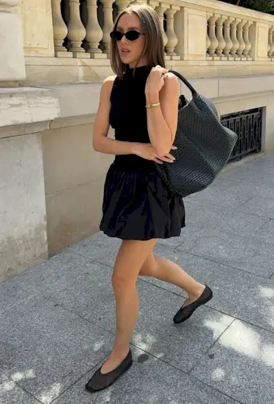 @emmaleger wears a black mini bubble-hem dress with ballet flats, sunglasses and a tote bag