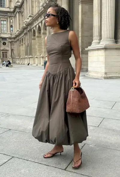 @slipintostyle wears a brown midi bubble-hem dress with dark brown heeled flip-flops, sunglasses and a tan woven leather clutch