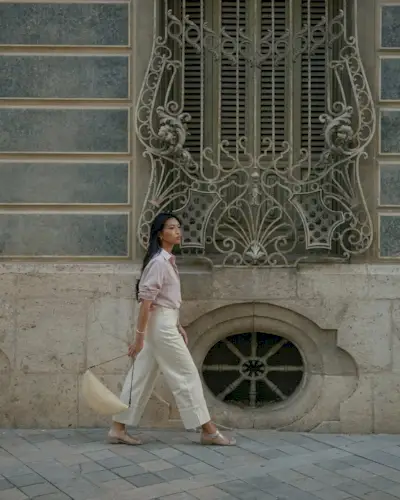 @michellelin.lin wears jelly fisherman sandals with a pink button-up, cream jeans and a raffia bag