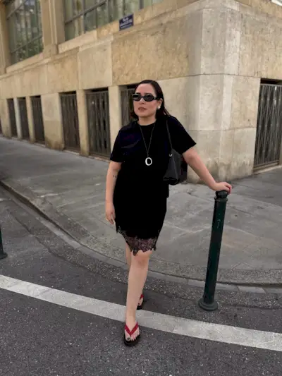 @indiraci wears leather flip-flops with a black t-shirt, lace-trim skirt and sunglasses