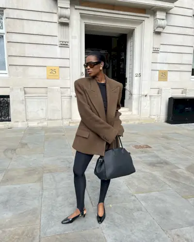 Fashion influencer @nlmarilyn wearing a chic winter outfit with black stirrup leggings.