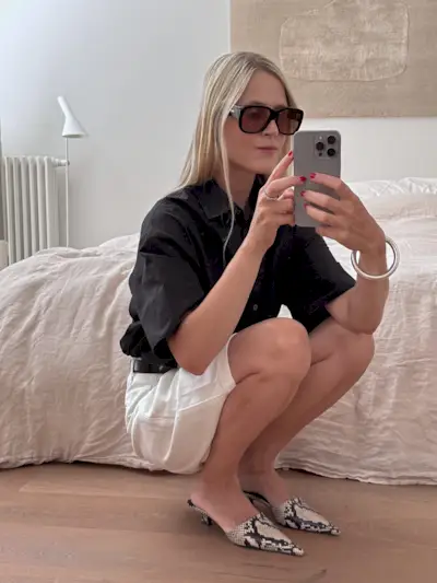 Influencer wearing snakeskin kitten heel mules.