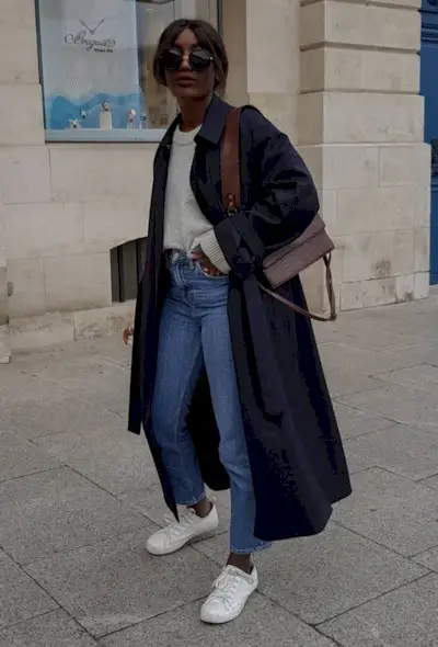 @aidabadji_ wears cropped flare jeans with a grey jumper, navy trench coat, white trainers and brown shoulder bag