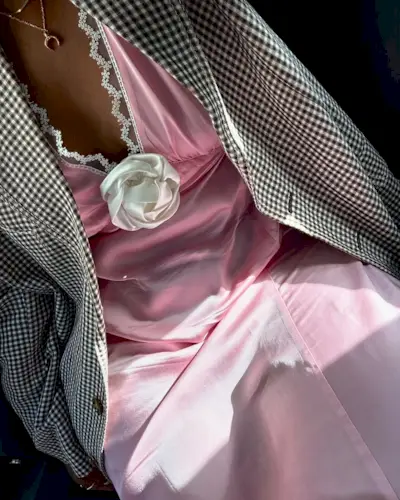 Woman wearing a pink dress with white flower and houndstooth blazer.