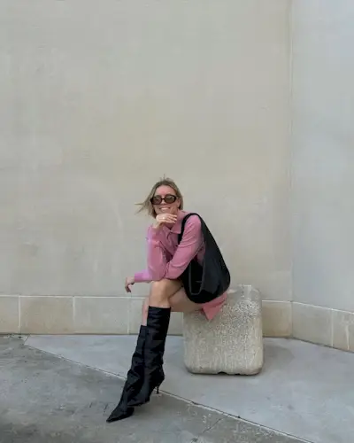 Woman wearing a powder pink dress and black boots.