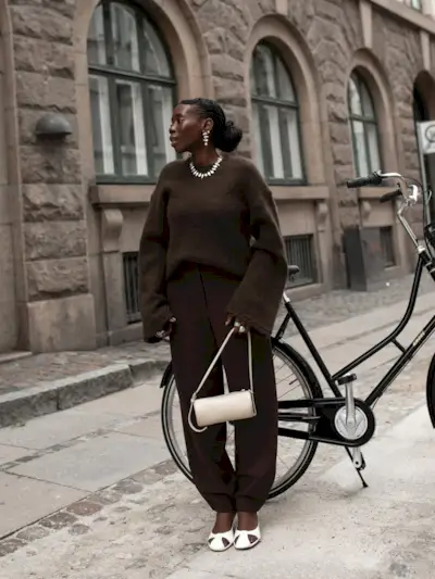 @daniellejinadu wears a pair of brown barrel leg trousers with a brown jumper