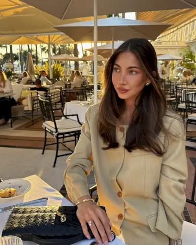 @fakerstrom wears a light beige collarless blazer with white jeans and a woven leather clutch