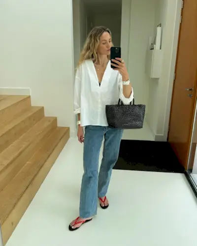 Woman wears white shirt, woven basket bag, blue jeans and red jelly sandals