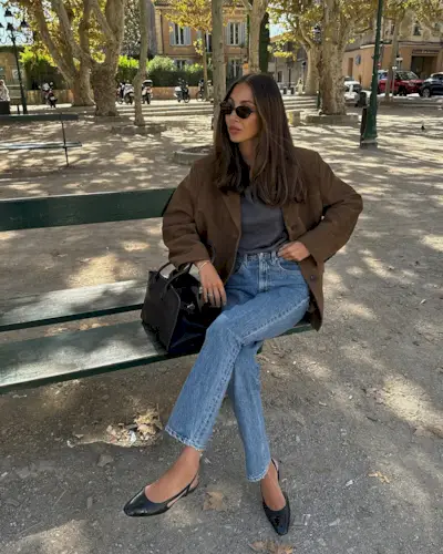 Woman wears brown suede blazer, red cardigan and blue jeans