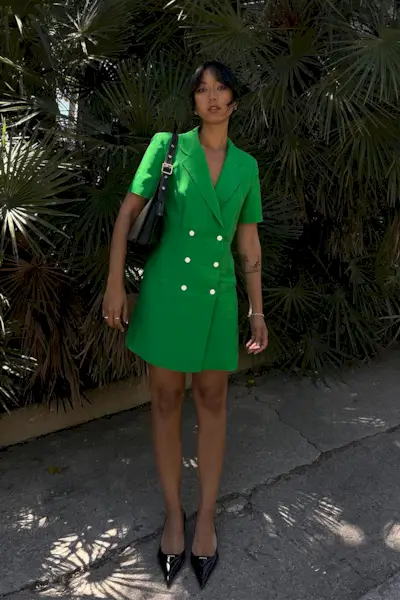 a photo showcasing one of the best summer work outfits with a woman wearing a green blazer dress with black slingback heels and a black shoulder bag