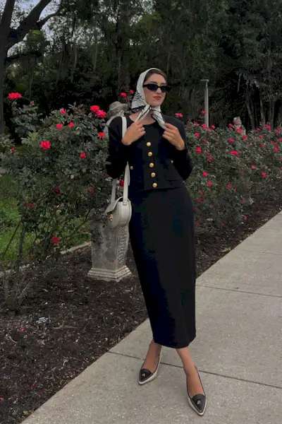 a photo showcasing one of the best summer work outfits with a woman wearing a black lady jacket with a black pencil skirt, black pumps, and a silk scarf