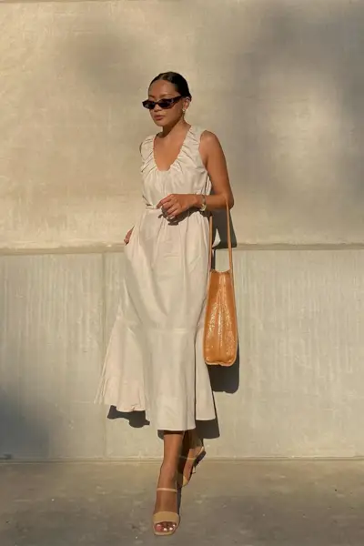 a photo showcasing one of the best summer work outfits with a woman wearing a tan dress with a tan handbag and tan sandals