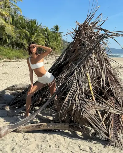 A woman standing wearing a white boy short bikini swimsuit.