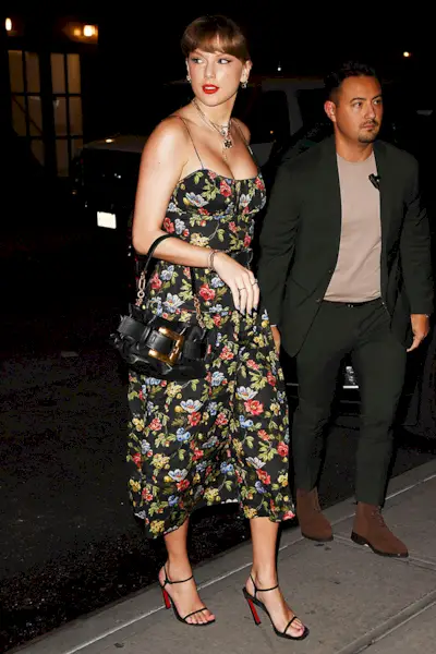 Taylor Swift wearing a black floral-print DOEN dress, a belt, Balmain bag, and Christian Louboutin heels to Via Carota in NYC