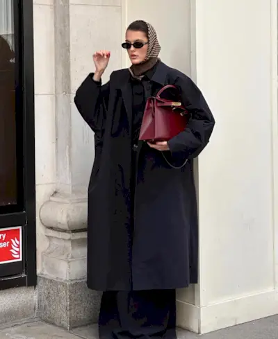 Influencer wears a navy trench coat.