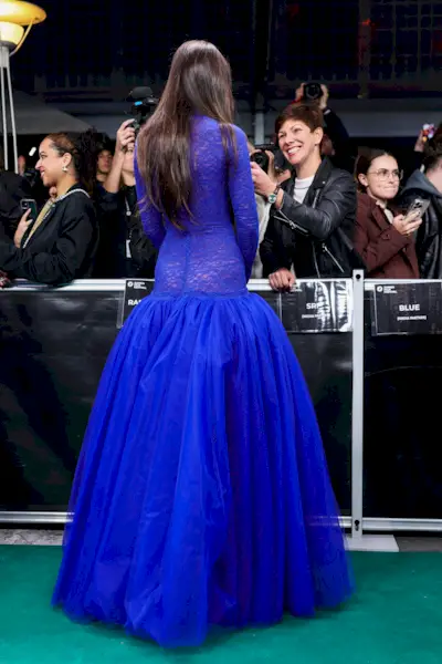 Dakota Johnson wears a bright blue gown on the red carpet in Zurich, featuring a drop waist silhouette and a sheer lace bodice