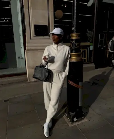 @nlmarilyn wears a knitted jumper and trouser outfit with loafers and a baseball cap