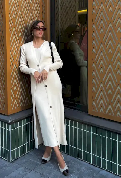 A woman's white outfit idea with knit dress styled with matching long cardigan and cap-toe flats.