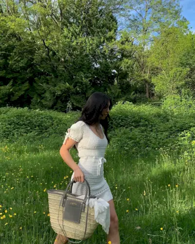 Woman walking in a field wearing a crochet dress.