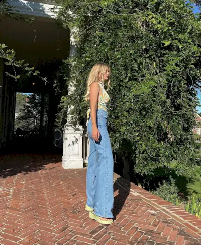 Woman wearing flared jeans and platform sandals.