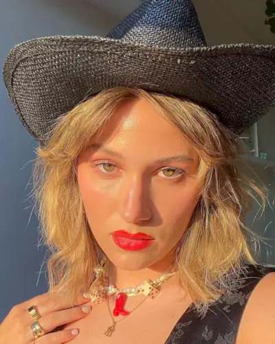 Woman wearing a straw cowboy hat and pearl charm necklace.